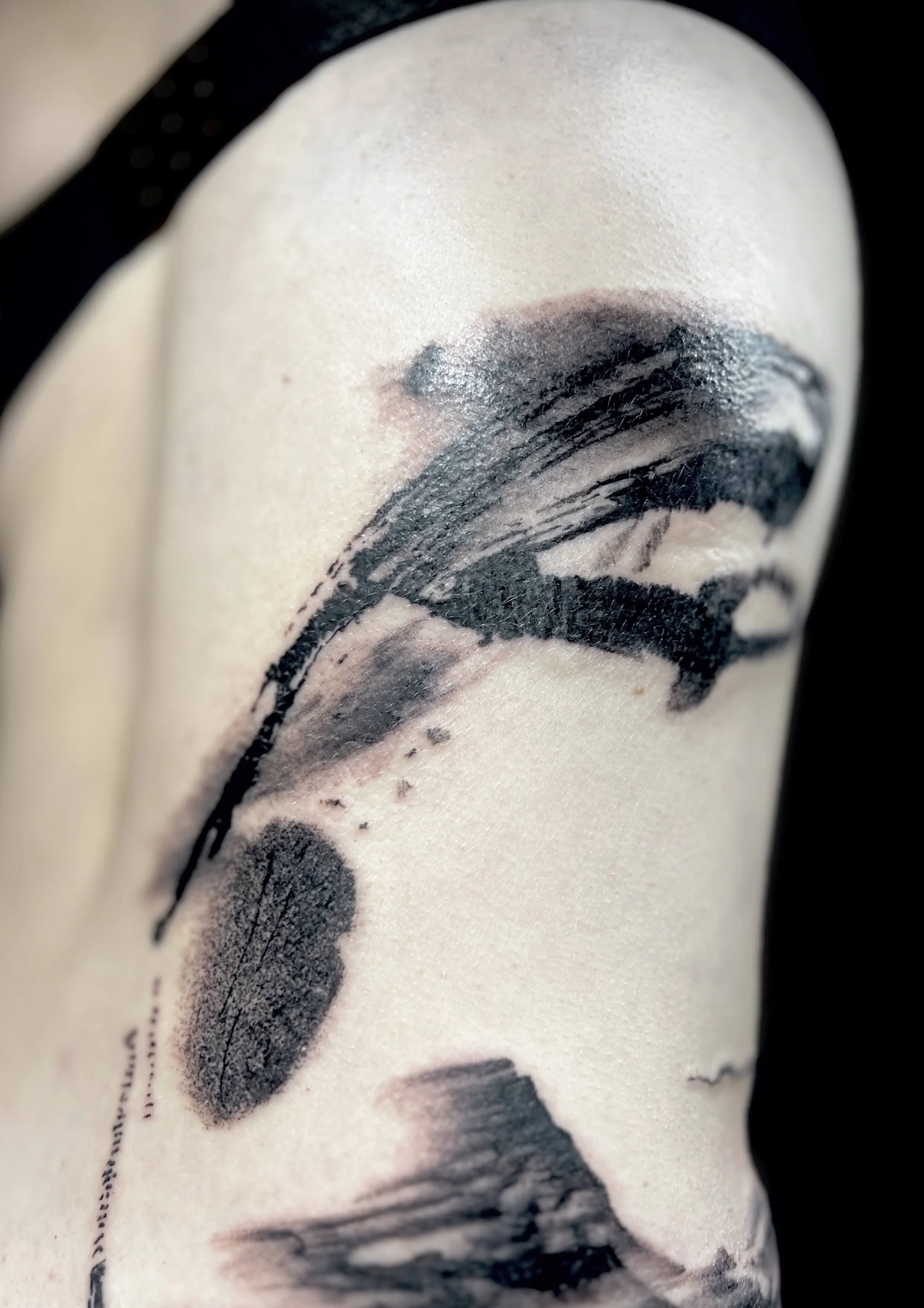 Detailed blackwork brush stroke tattoo with fine linework.