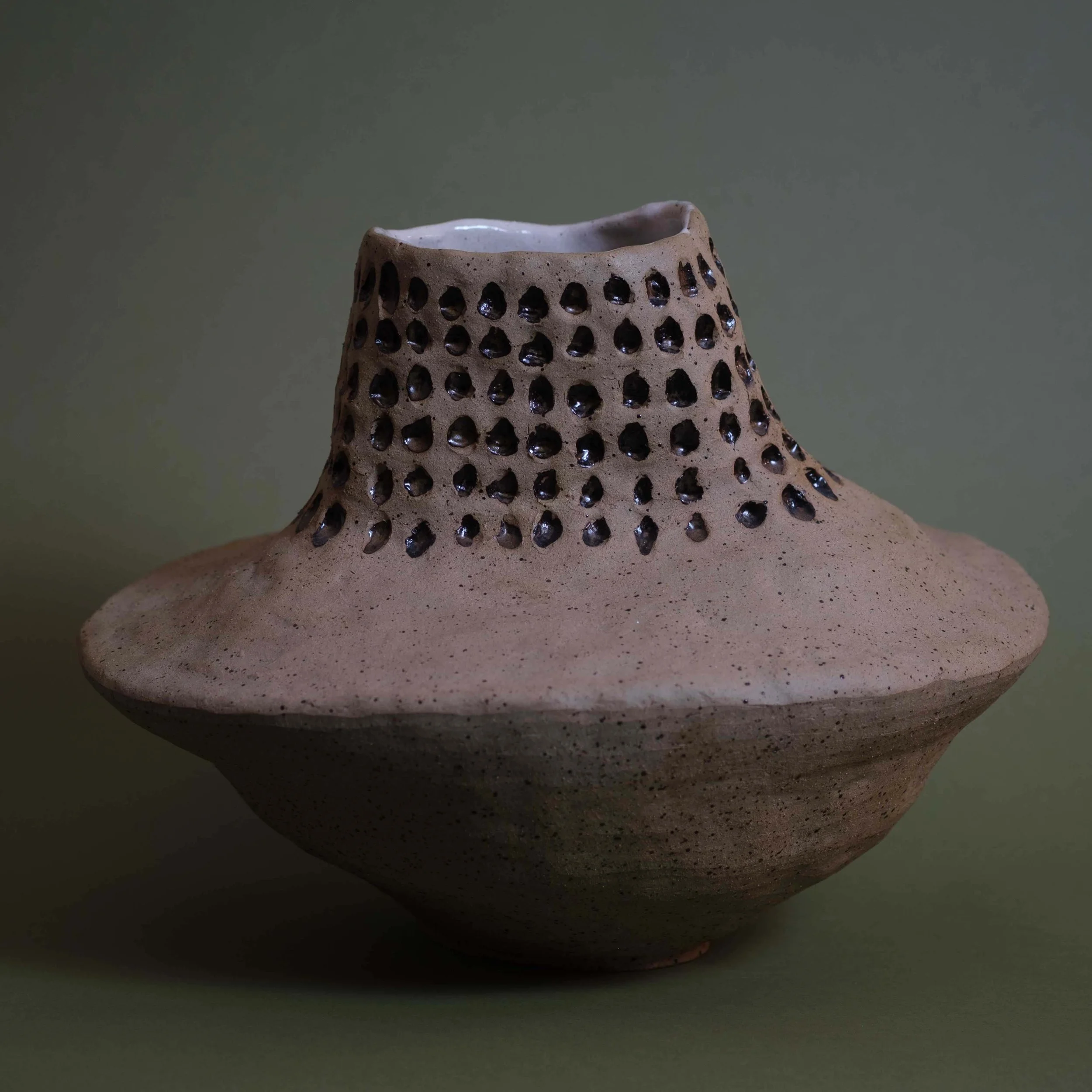 Side view of Dip in Space sculptural pottery highlighting its wide base and textured perforated structure