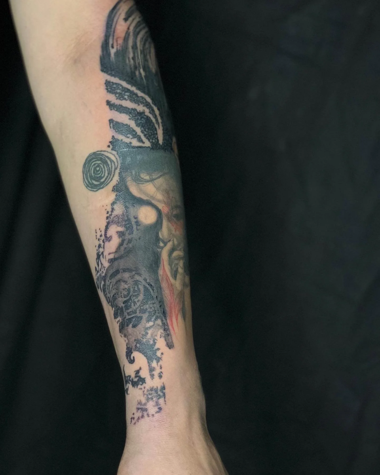 Abstract portrait tattoo with flowing, organic linework and layered swirl elements on the arm.