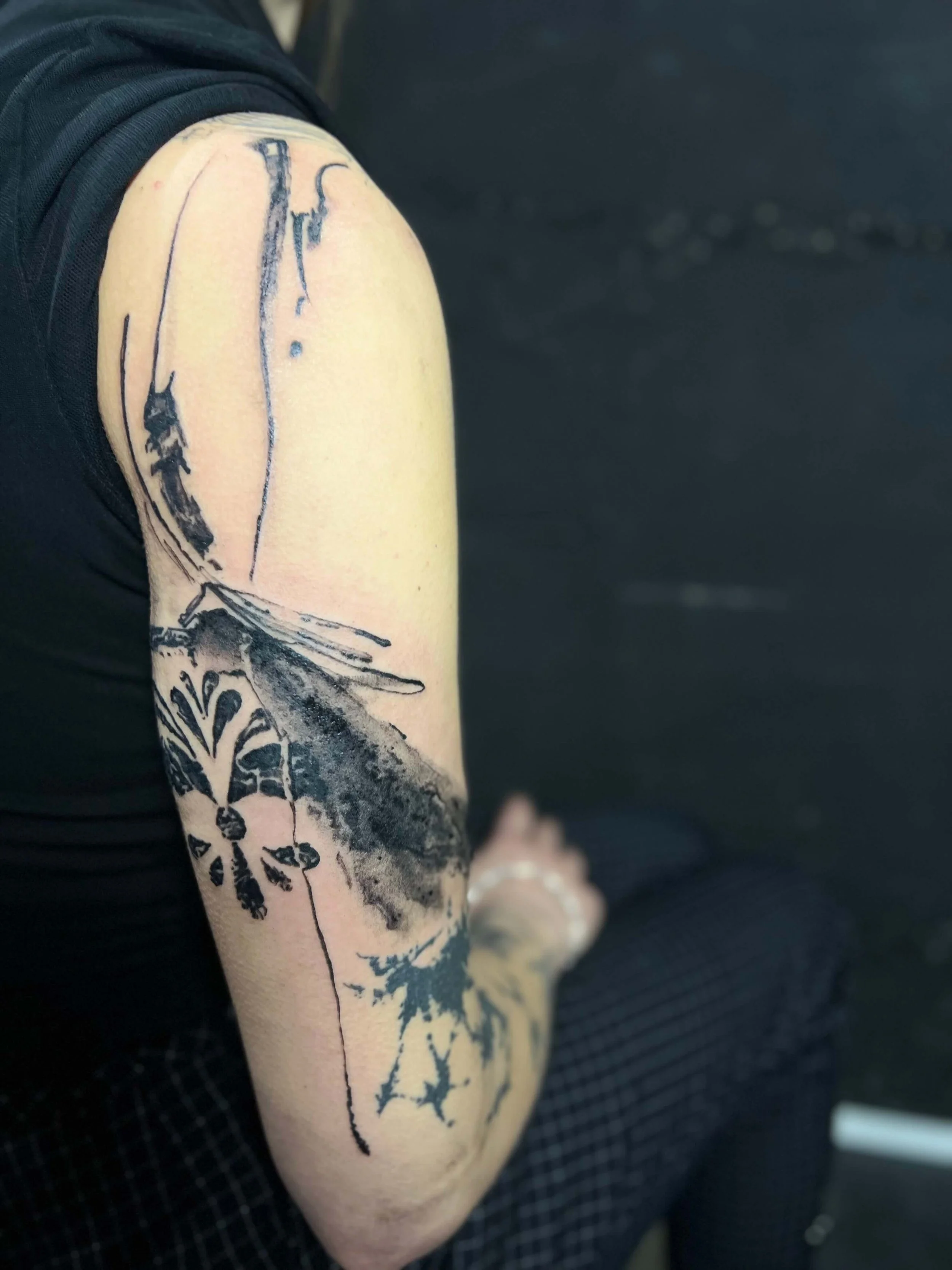 Abstract blackwork tattoo combining floral elements with expressive ink linework.
