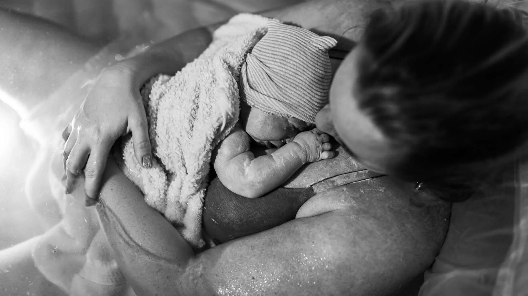 A person giving birth to a baby in a hospital setting, with the newborn resting on the mother's chest.