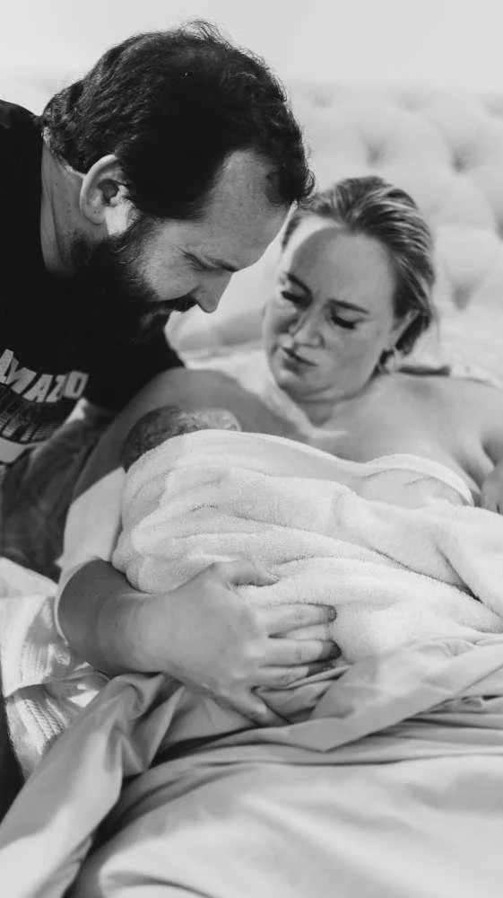 Midwife and husband holding their newborn after a wonderful water birth.