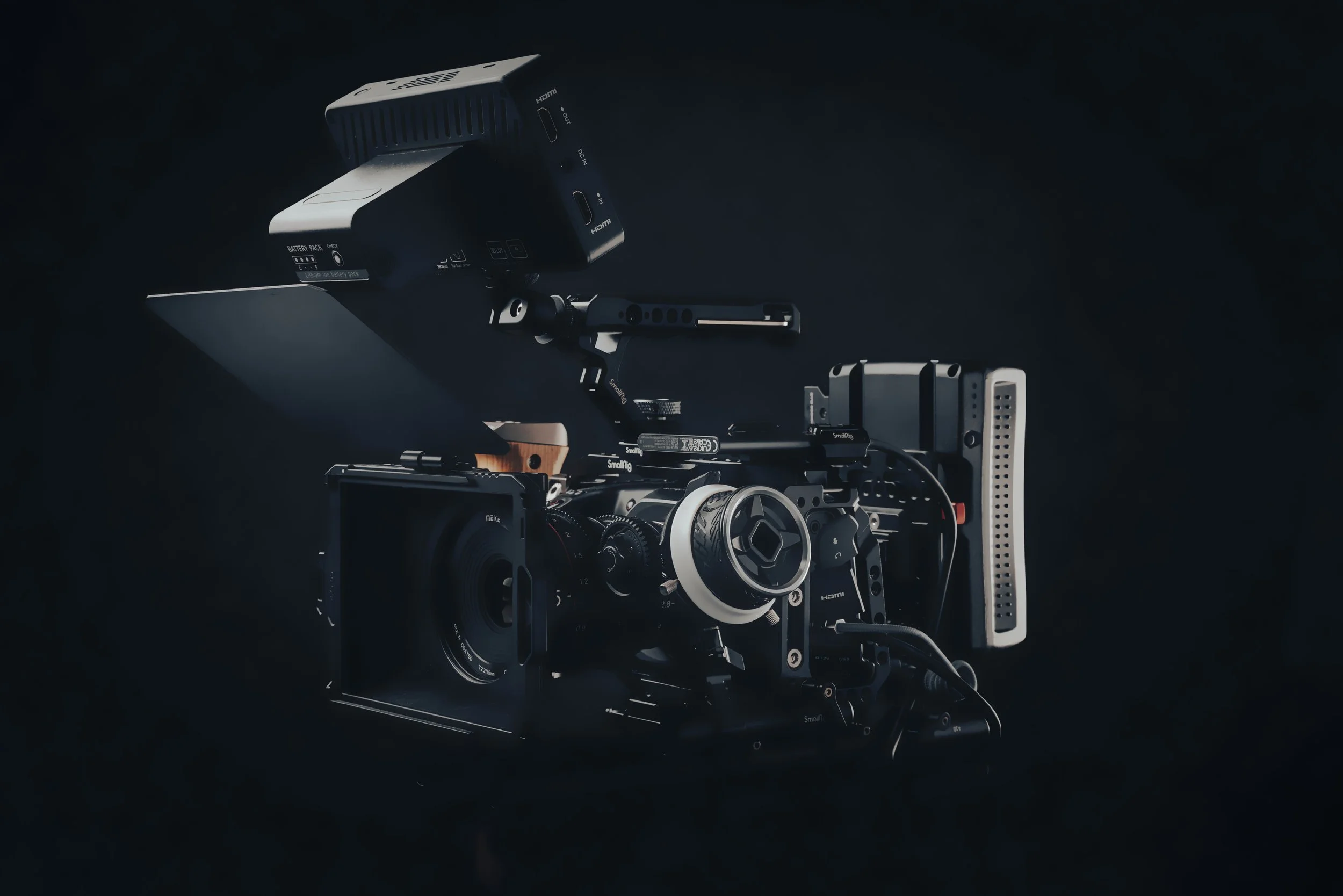 Een professionele camerastudio met een zwarte camera, onder aangepaste apparatuur en accessoires, op een donkere achtergrond.