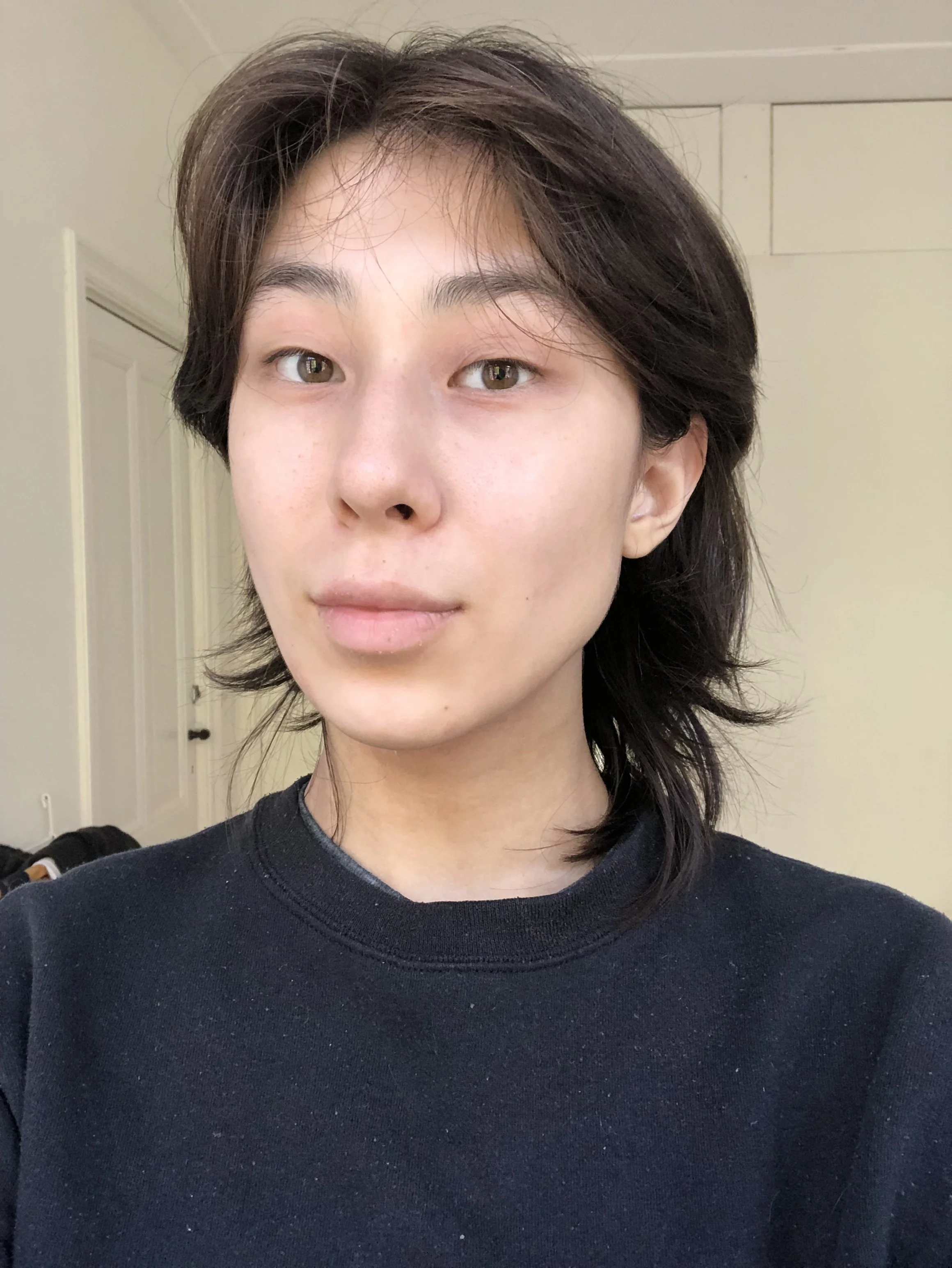 Person i svart tröja med axellångt hår, inomhus.