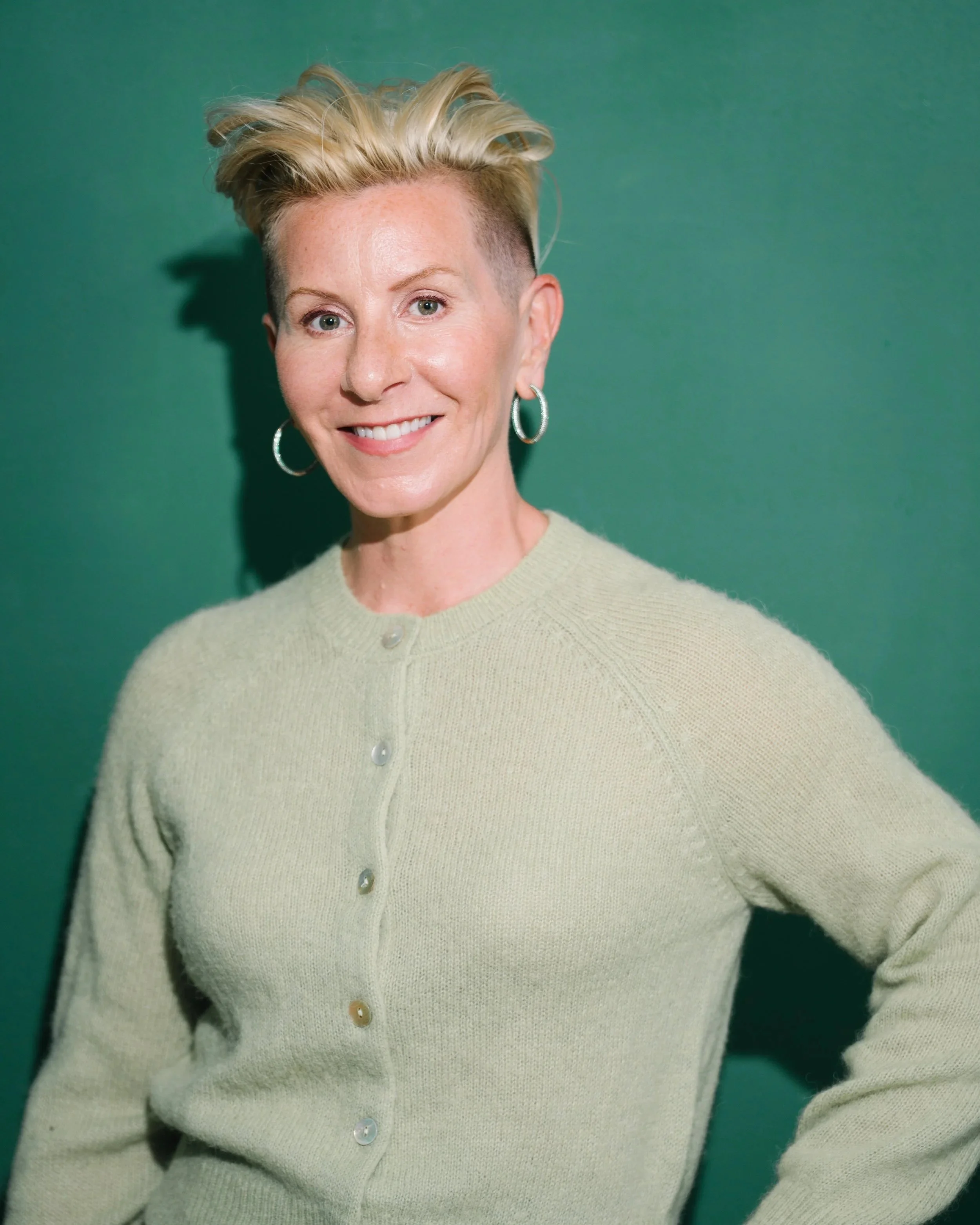 Jenny Skoog Mondesir, writer and podcast producer, smiling in front of a green wall