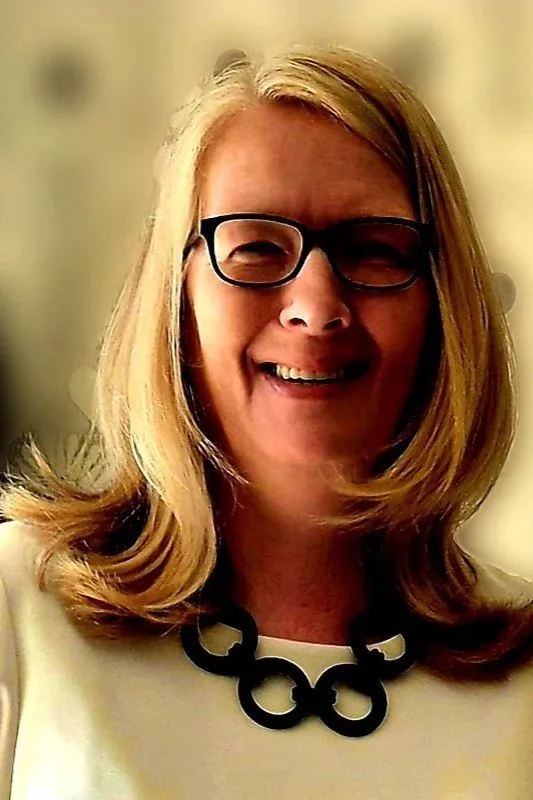 Johanna wearing glasses, and a black necklace, smiling at the camera.