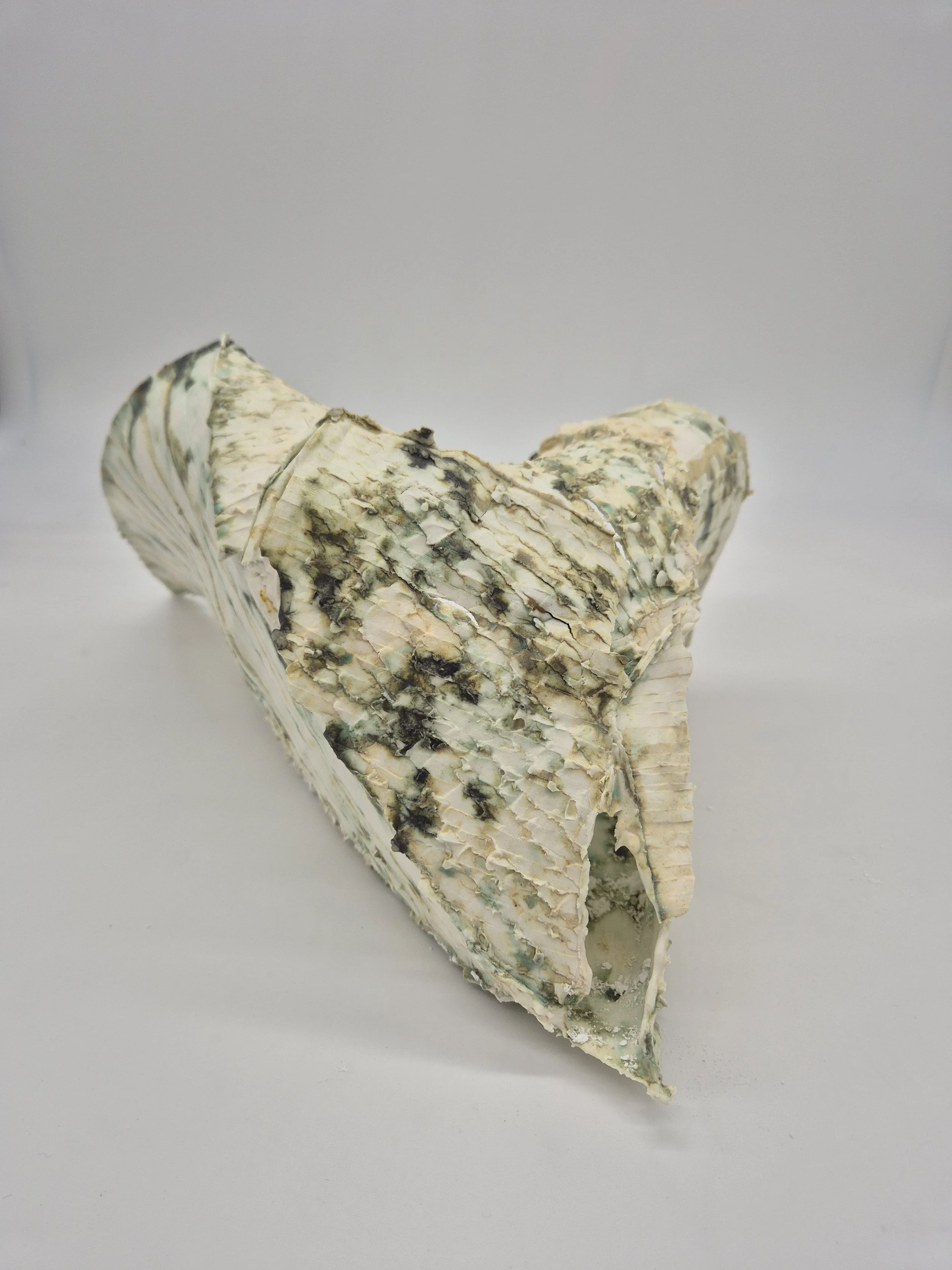 Keramisch kunstwerk dat lijkt op blauwaderkaas op witte achtergrond