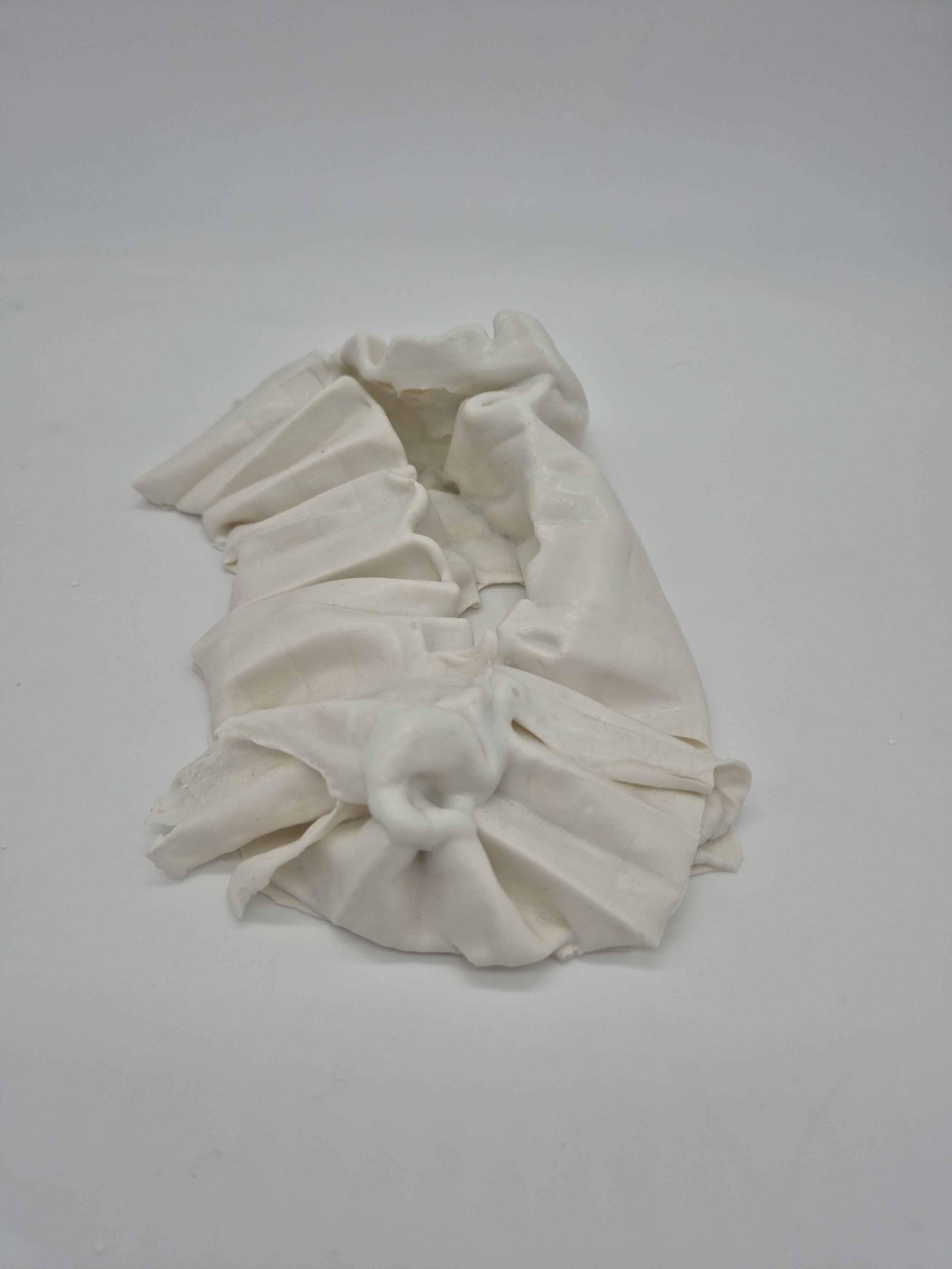 Een wit, gevouwen ceramisch object op een witte achtergrond.
