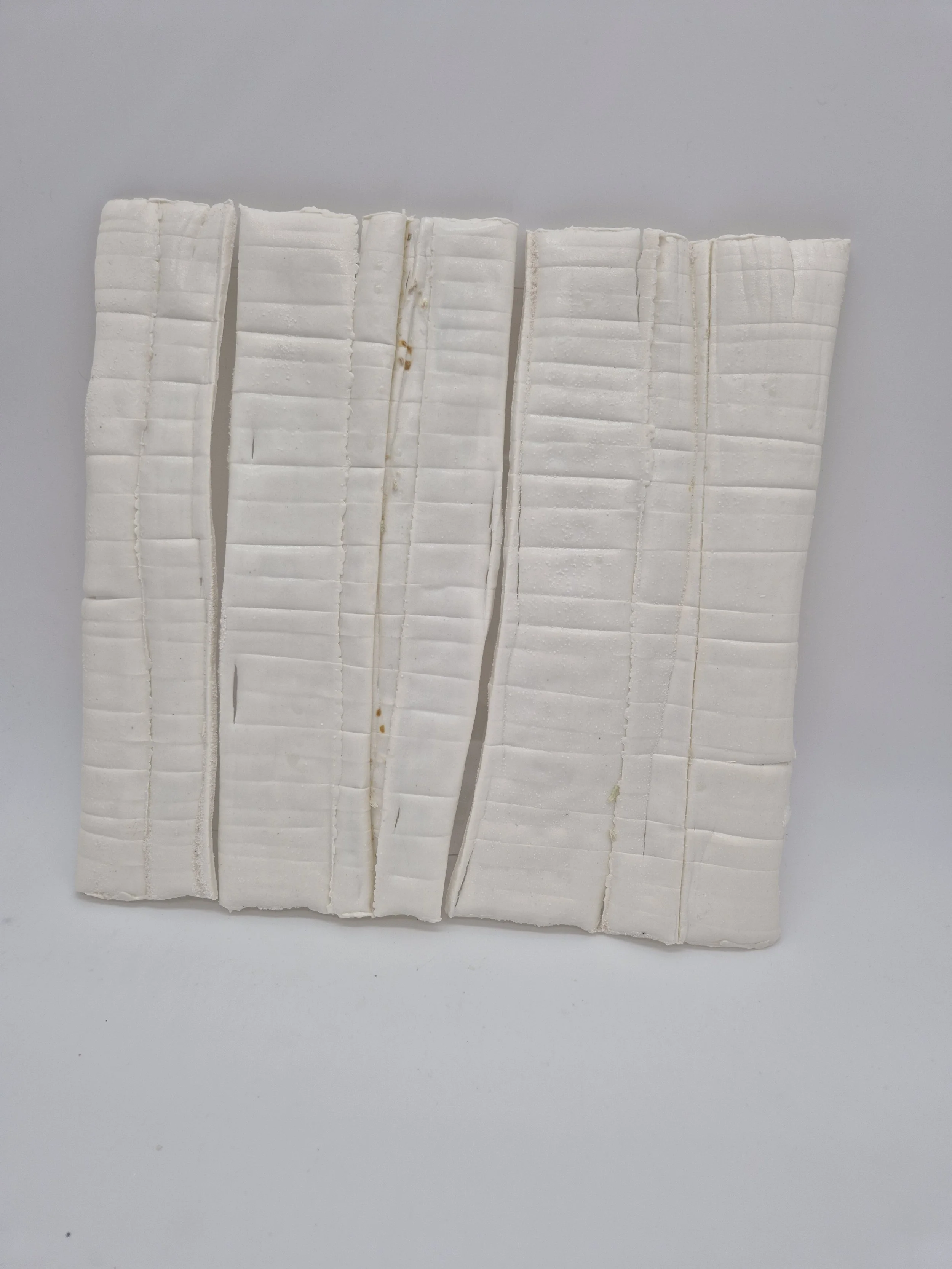 Gelaagde witte keramische structuur met verticale lijnen