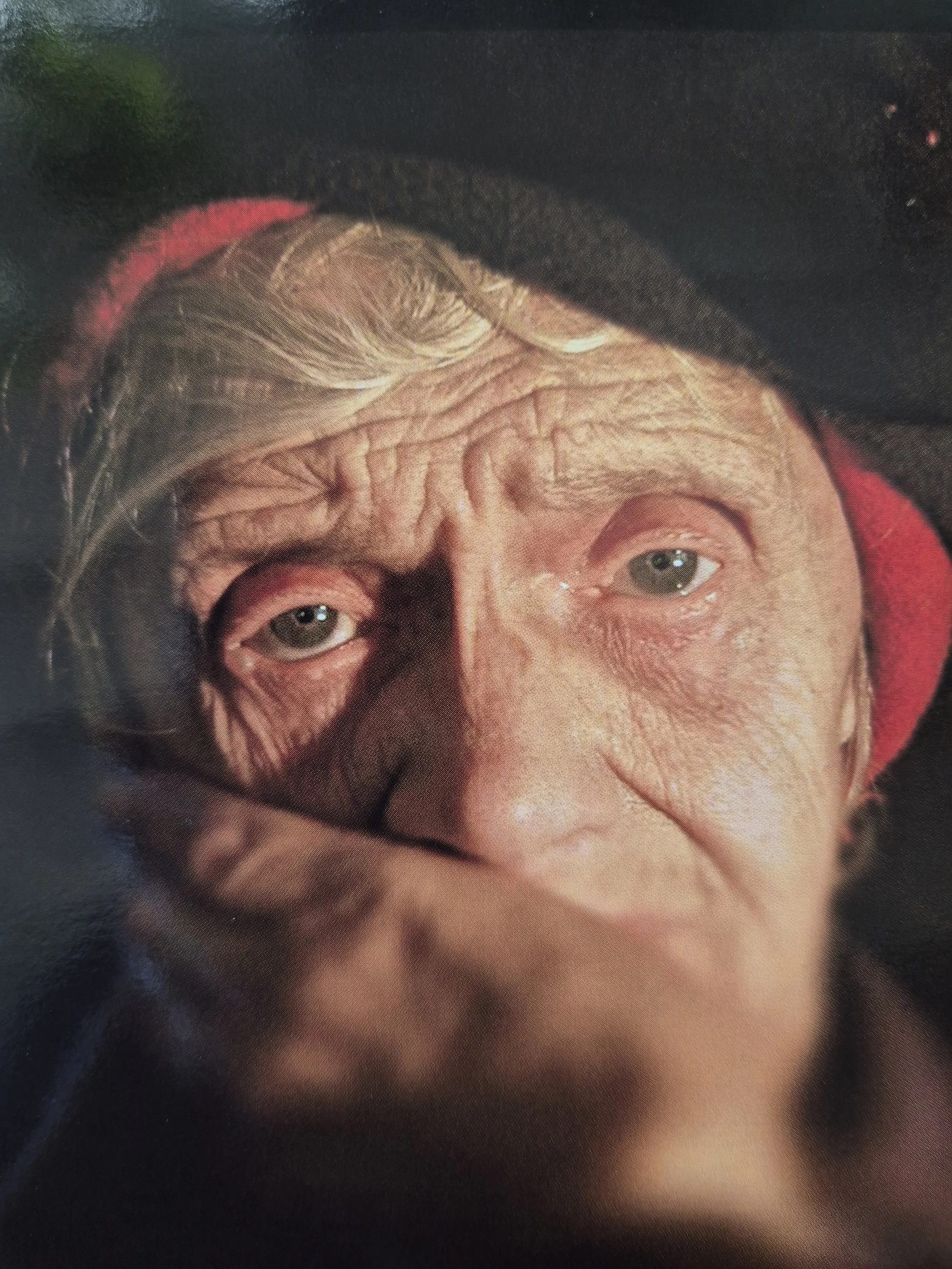 Portret van een oudere persoon met een verweerd gezicht en een hand voor de mond. Rotterdamse dak- en thuisloze.