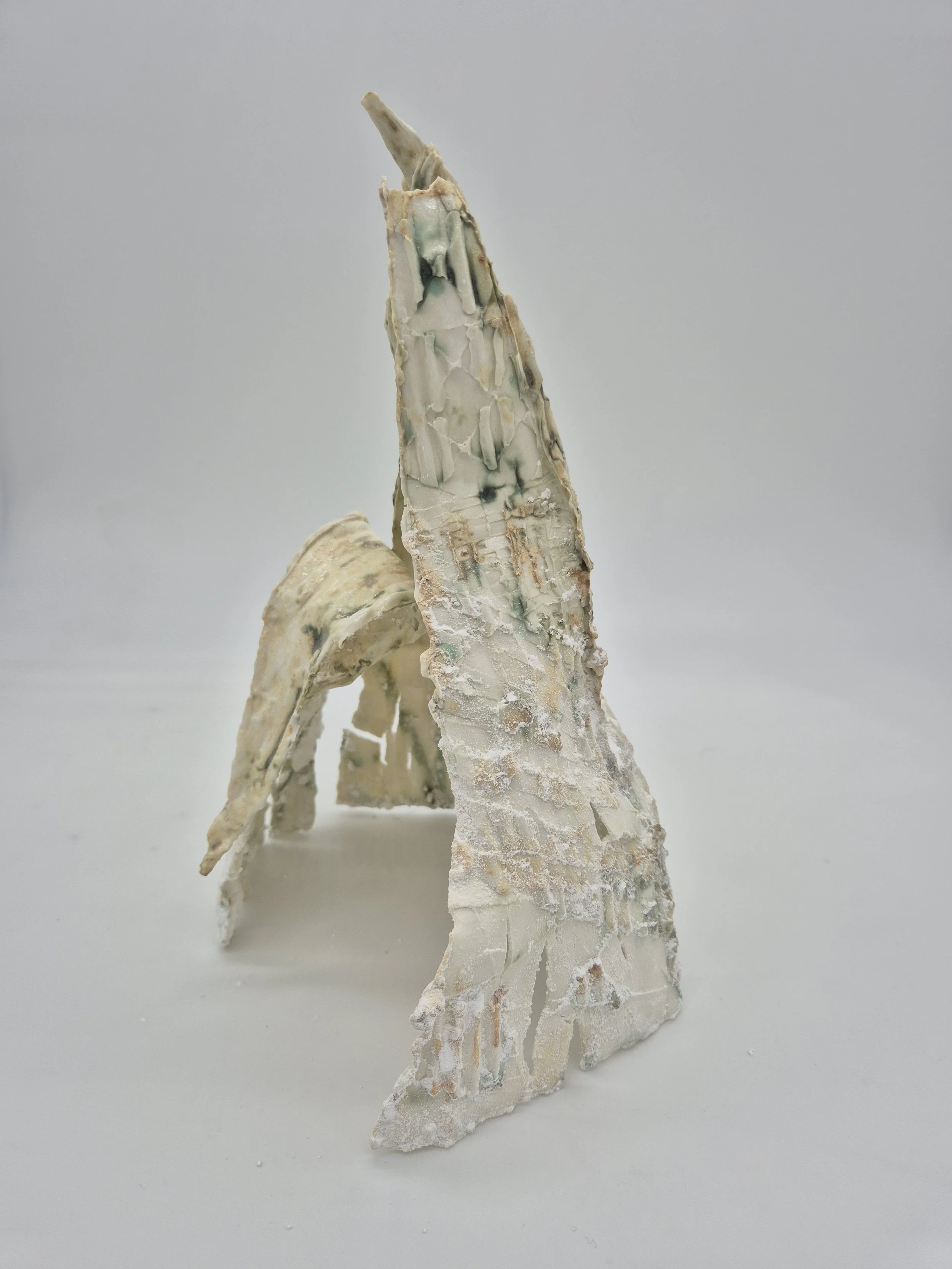 Abstracte sculptuur van gekrulde en puntige vormen in lichtgekleurde tinten tegen een witte achtergrond.