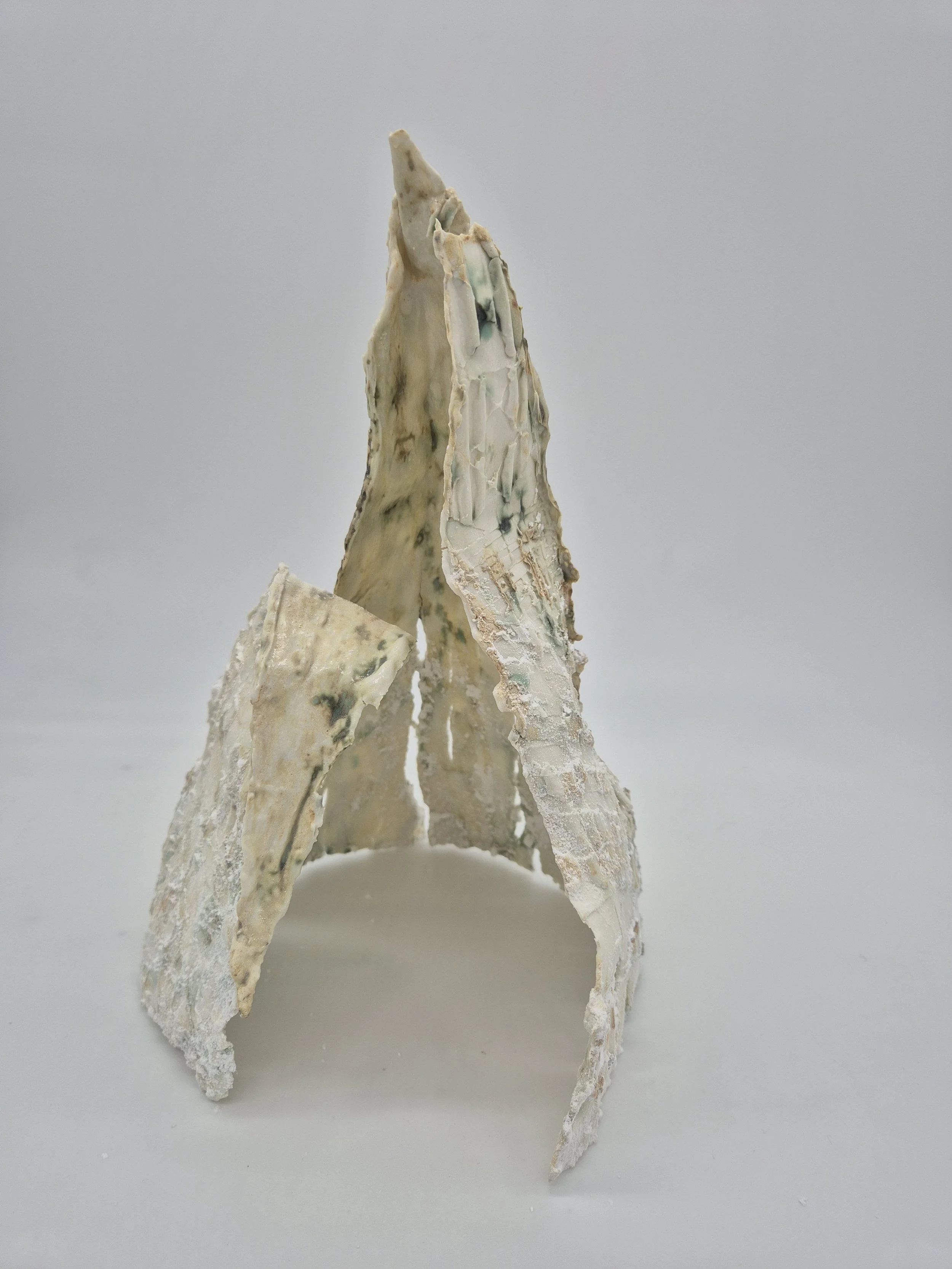 Abstracte sculptuur van wit en beige materiaal met een ruw oppervlak op een grijze achtergrond.