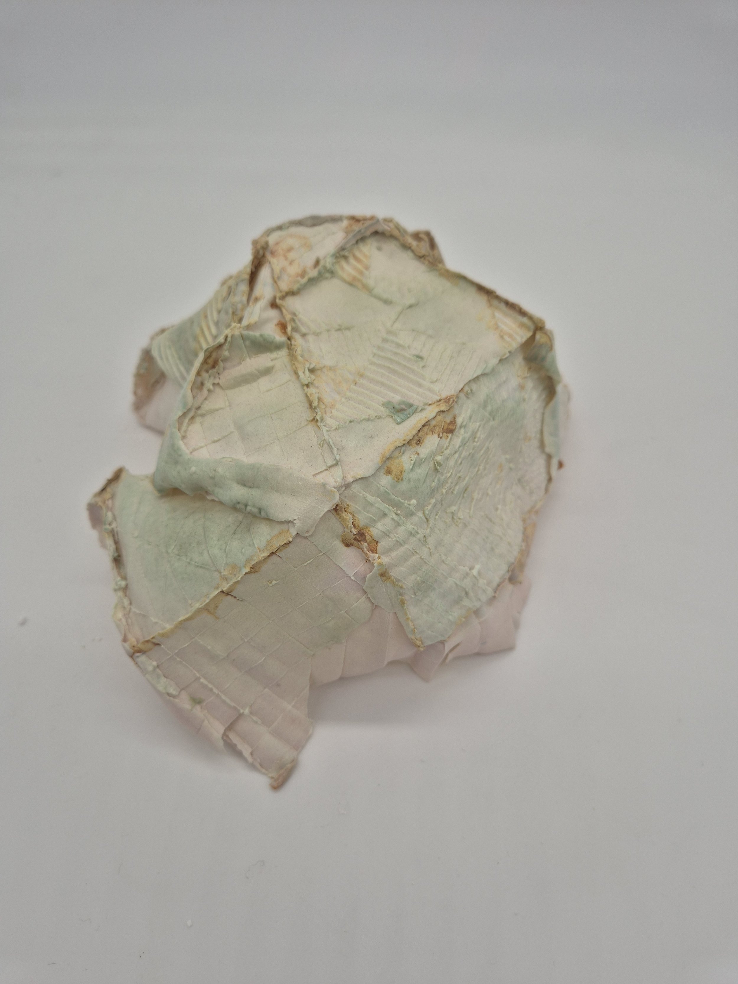 Gekreukelde groene en beige papieren bol op een witte achtergrond