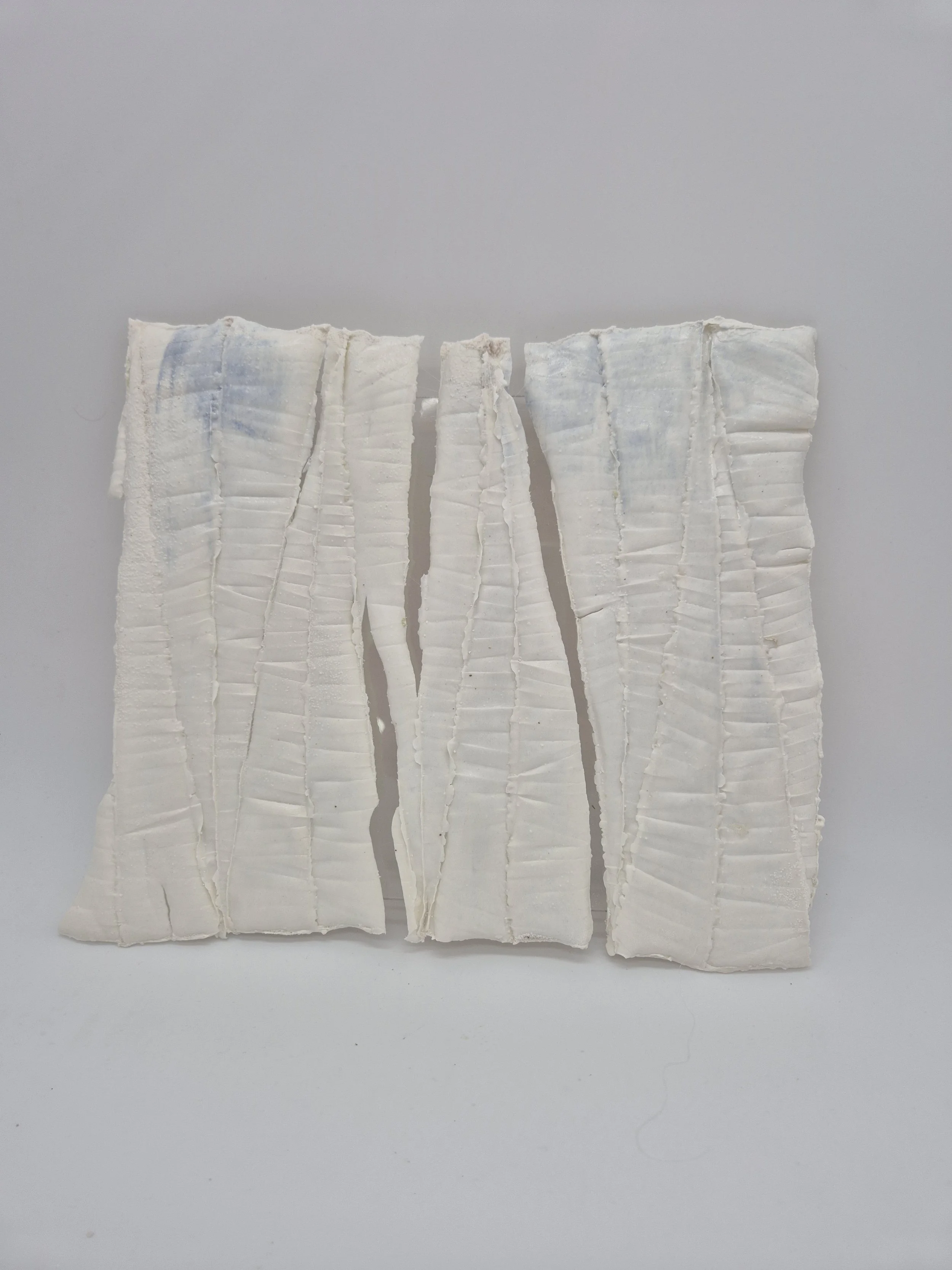 Wit abstract kunstobject met verticale lijnen en lichte blauwe accenten, verdeeld in twee delen.