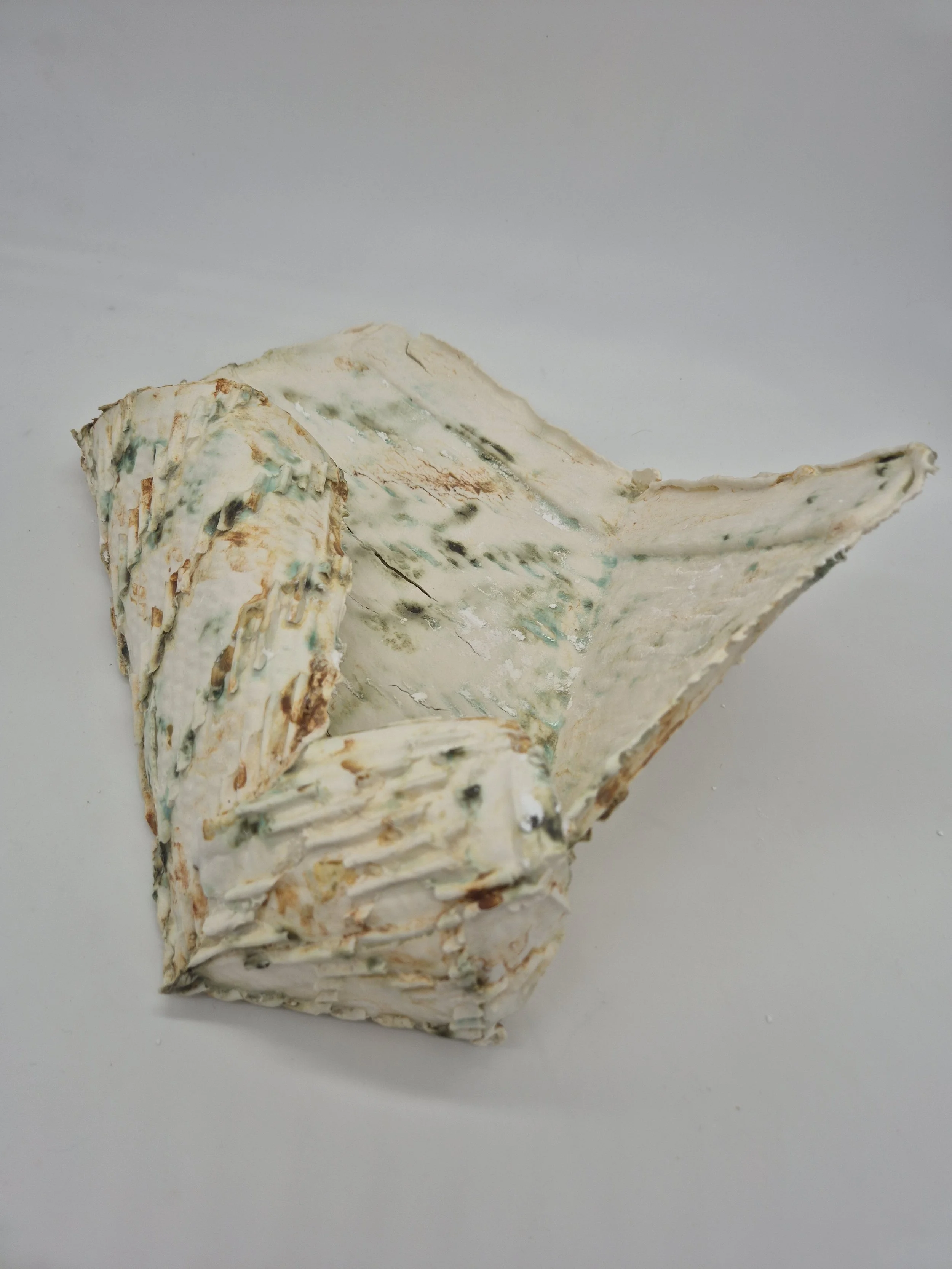 Keramisch kunstwerk met organische vormen en wit met groenachtige en bruine accenten.