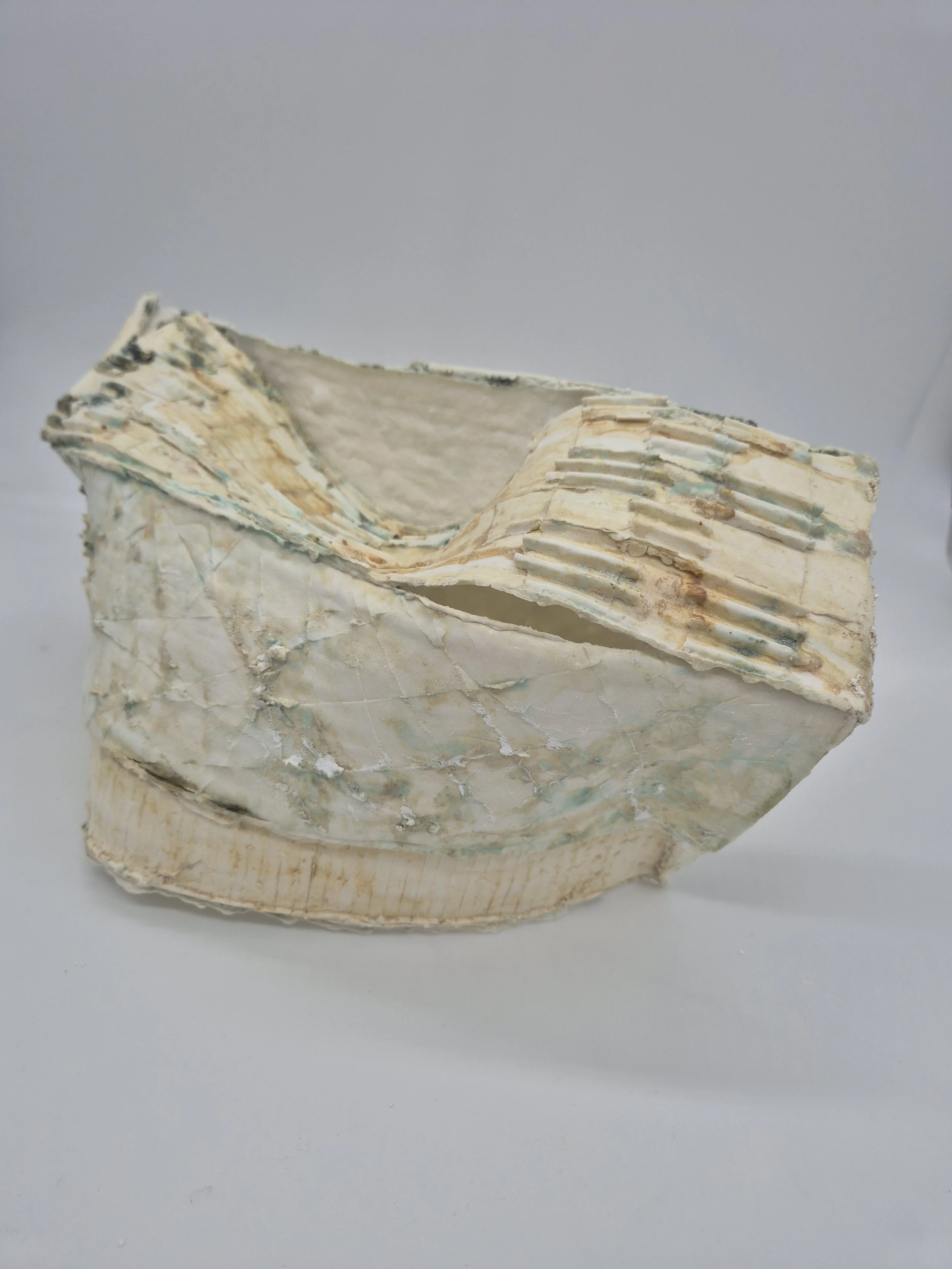 Abstracte, gegolfde structuur van keramiek met textuur en vouwen, op een witte achtergrond.