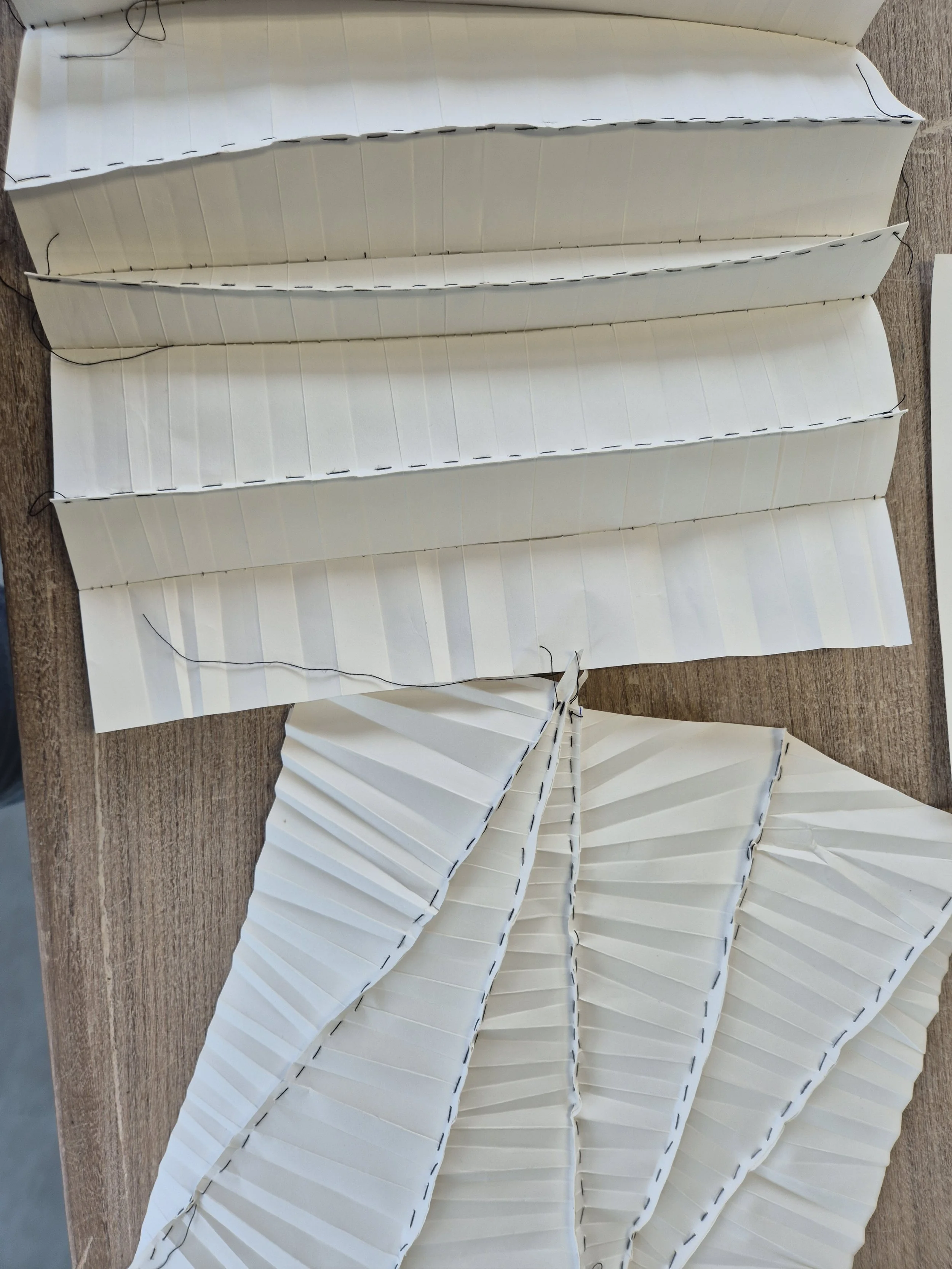 Papieren met plooien en stiksels op een houten tafel.