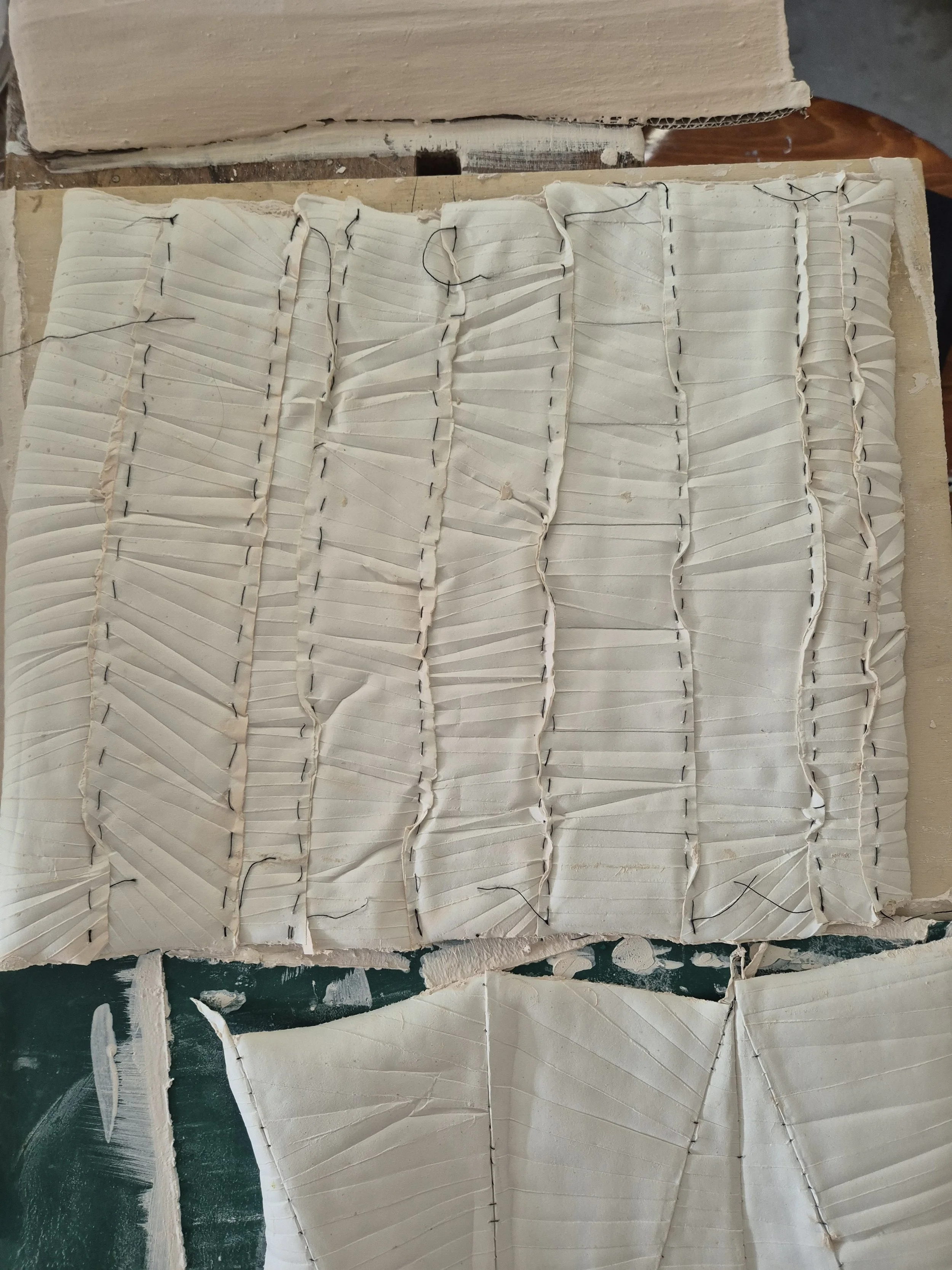 Gesneden kleimodel met gestikte lijnen op houten achtergrond.