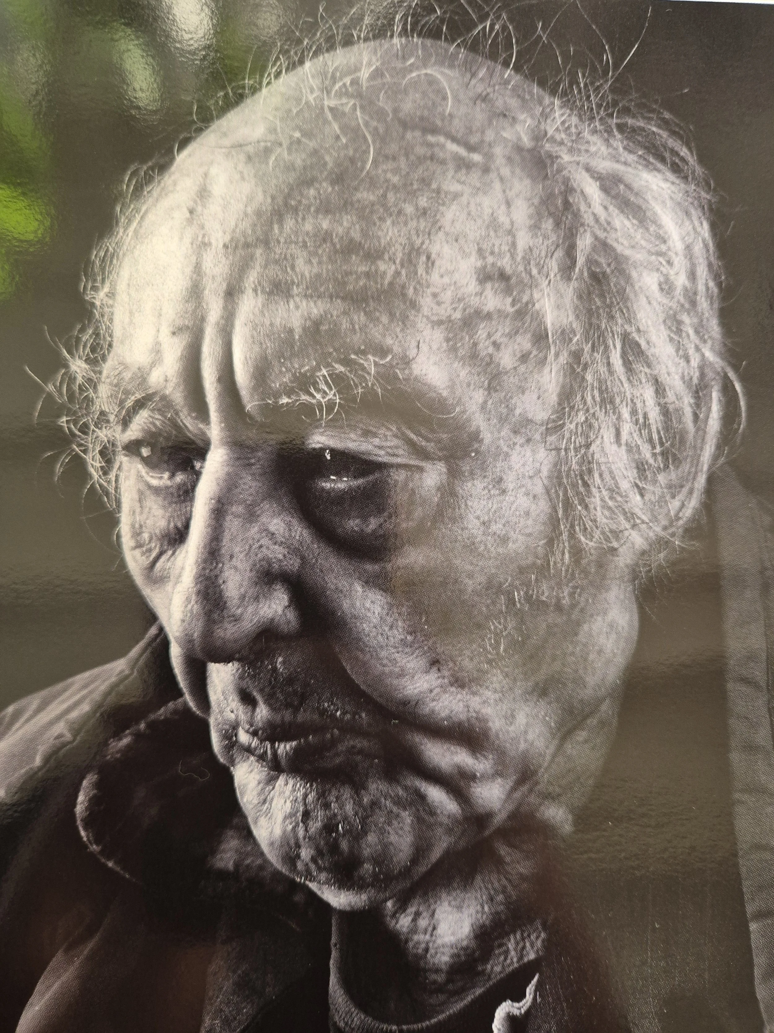 Zwart-wit foto van een oudere man met een ernstig gezicht en wit/grijs haar. Rotterdamse dak- en thuisloze.