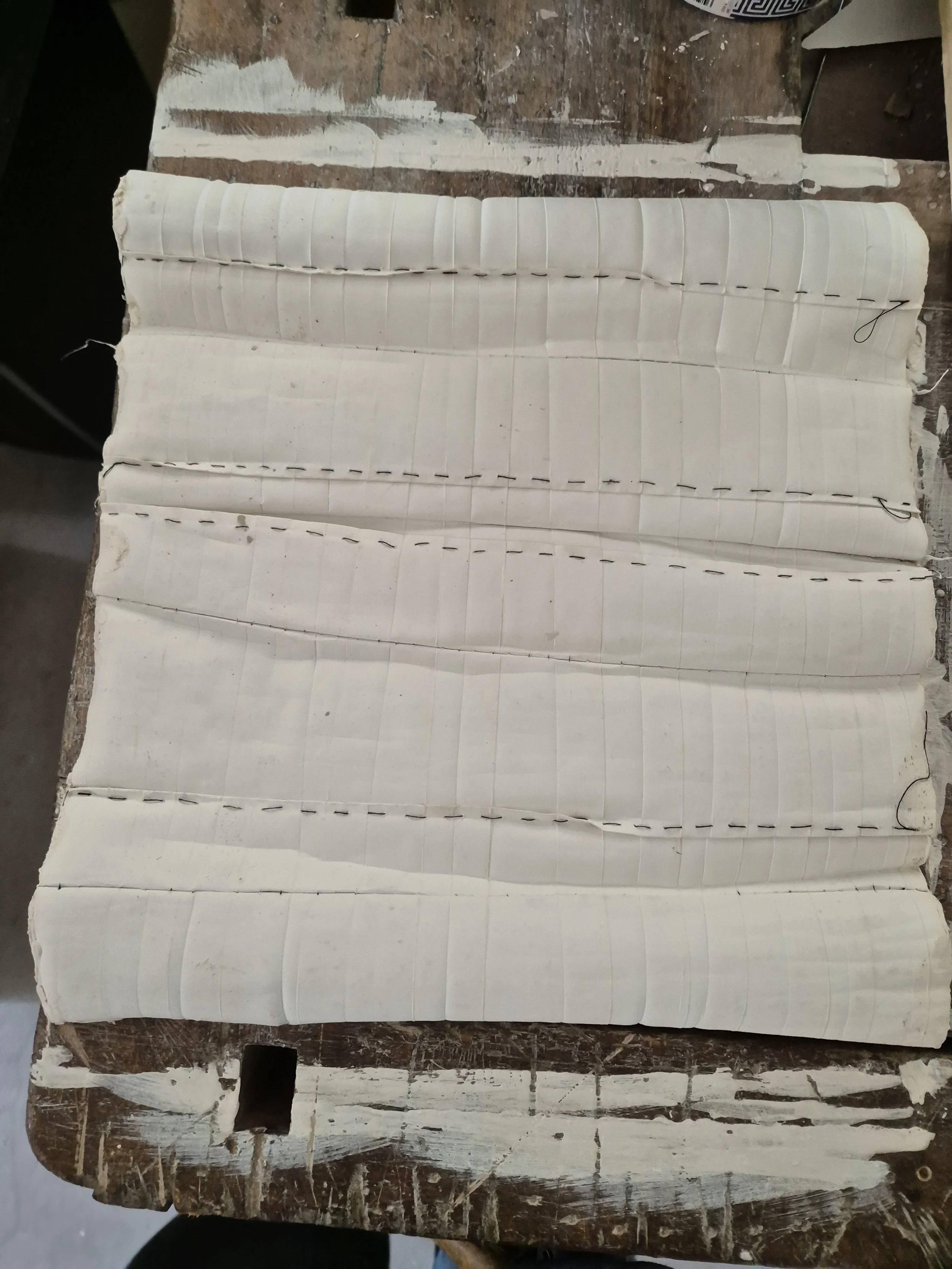 Een stuk papier met lijnen en stiksels op een houten tafel.