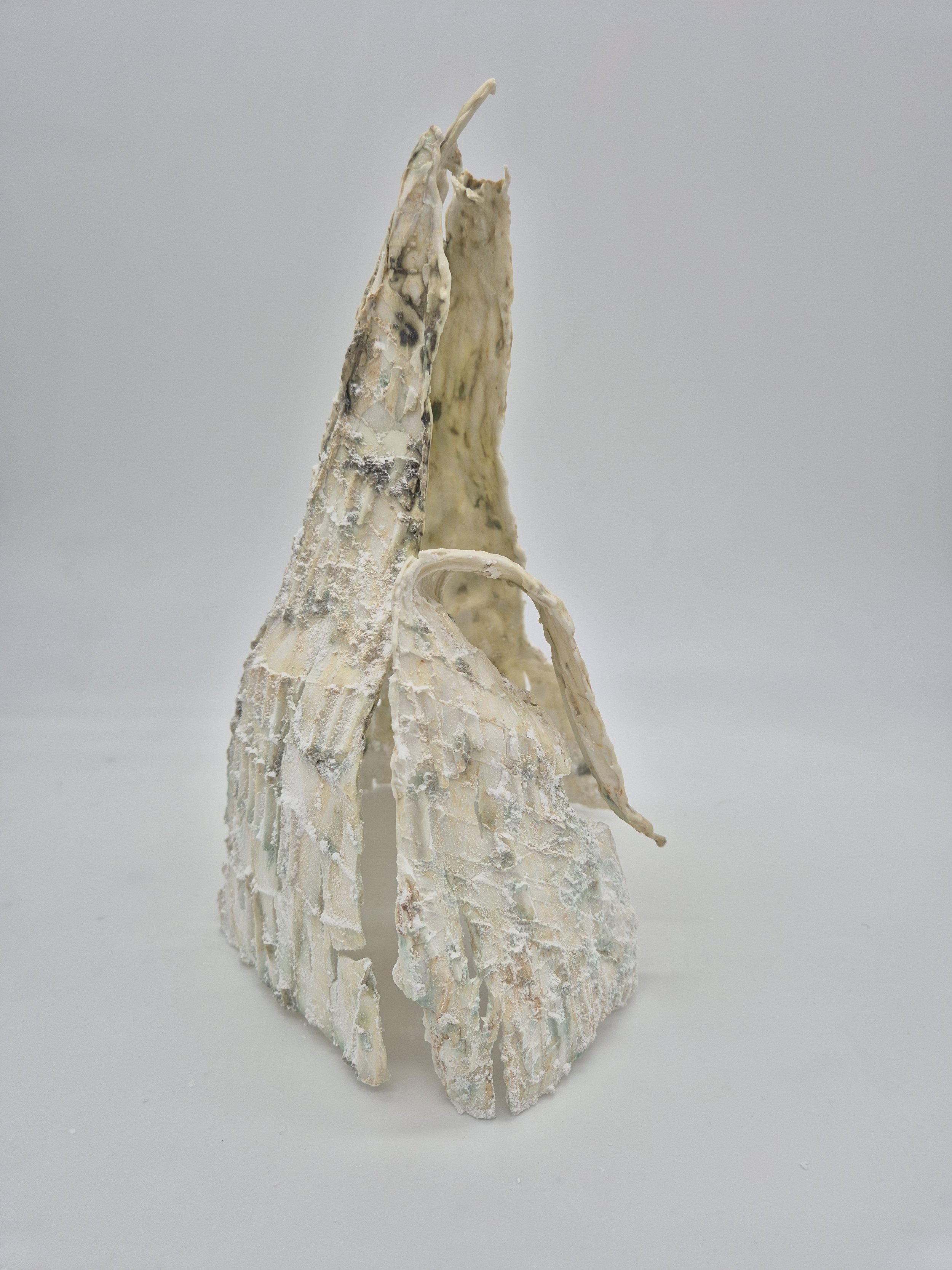 Abstracte sculptuur van gestructureerd materiaal met een gebroken, golvende vorm.