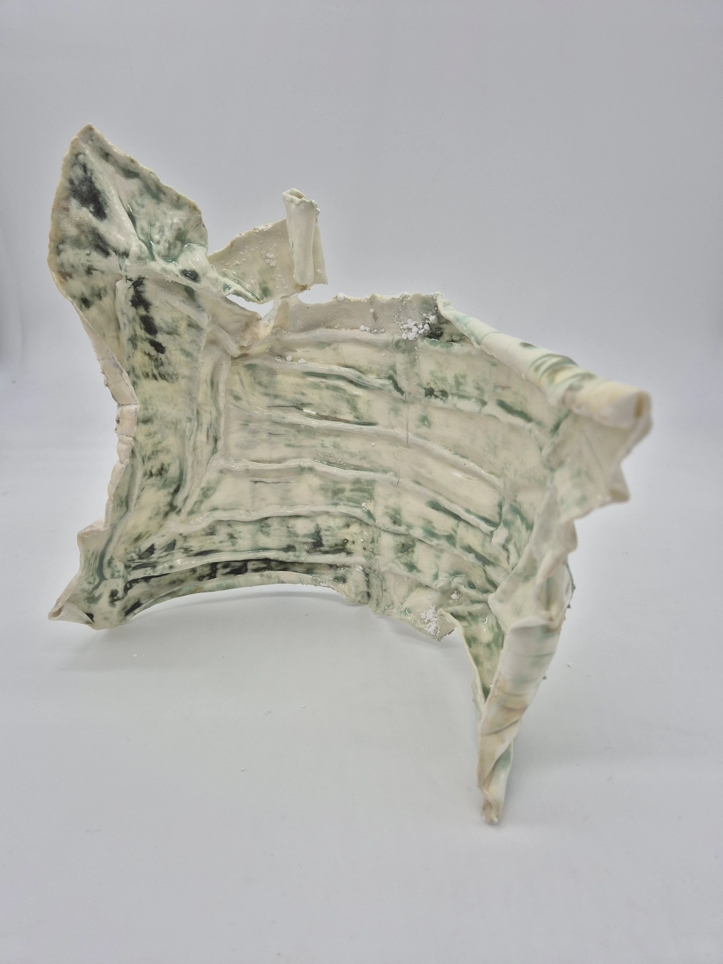 Abstracte keramische sculptuur met groene en witte tinten op een witte achtergrond.