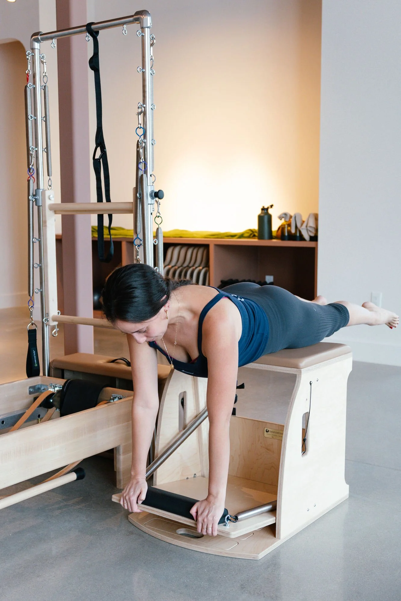 A woman performing Pilates exercise on a reformer machine at Monument Pilates in Plugerville, TX
