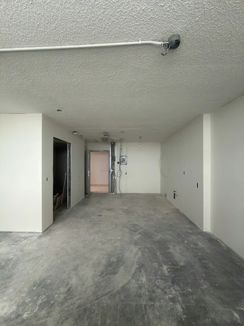 Empty unit during renovation with bare grey concrete floor and white walls