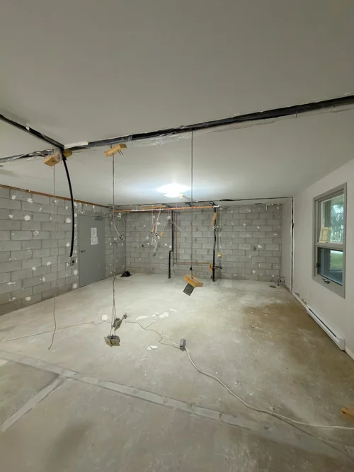 Unfinished room with concrete block walls and wires hanging from ceiling
