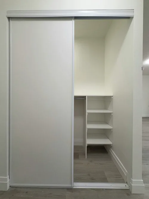 Finished closet with white sliding door and white shelving