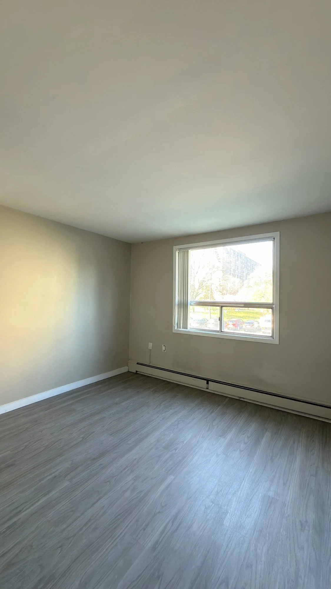 Empty room with freshly painted neutral walls, a window and a new wood-look plank floor