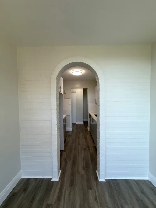 White painted brick wall with an arched doorway, grey side walls and baseboards