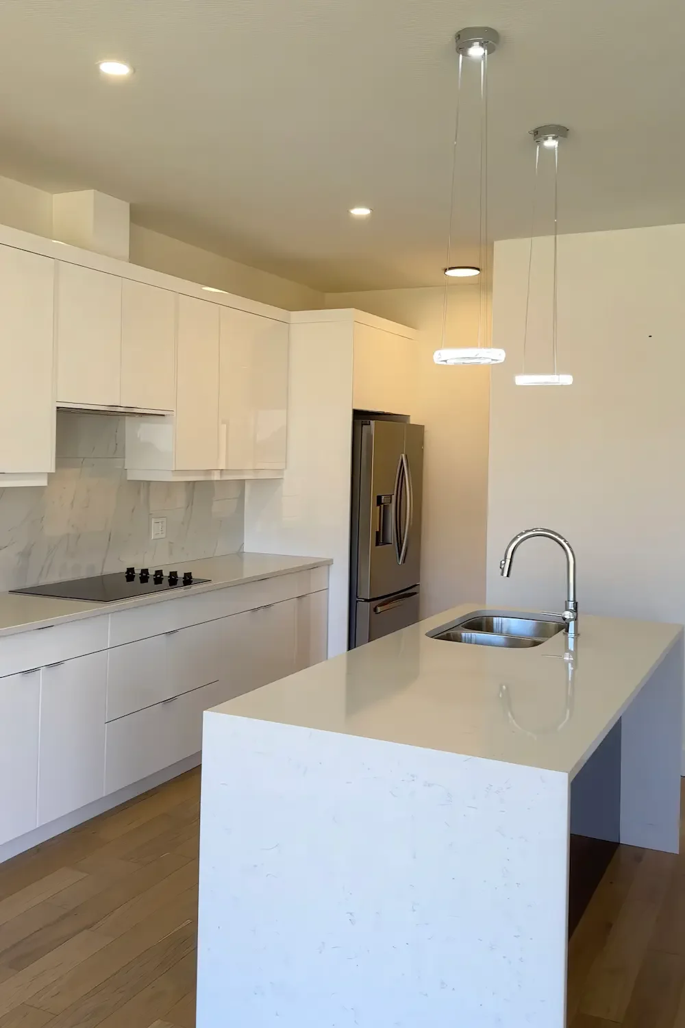 Modern white kitchen renovation with custom island and pendant lighting in London, Ontario.