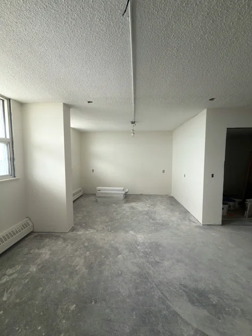 Empty room during renovation with bare grey concrete floor and a textured ceiling