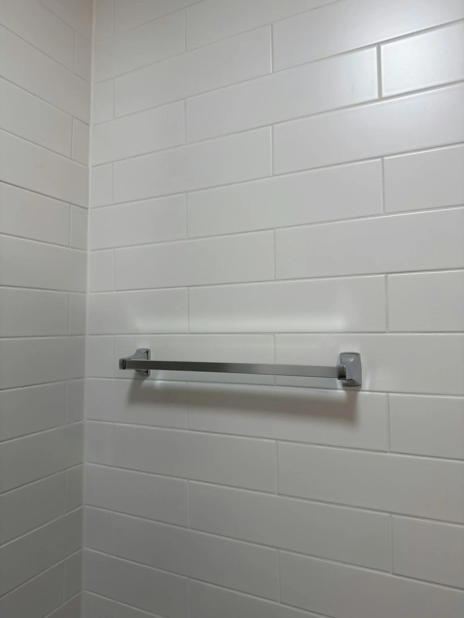 Finished white wall tile with a chrome towel bar mounted across it