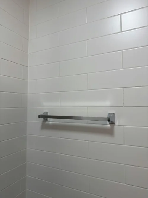 Finished white wall tile with a chrome towel bar mounted across it