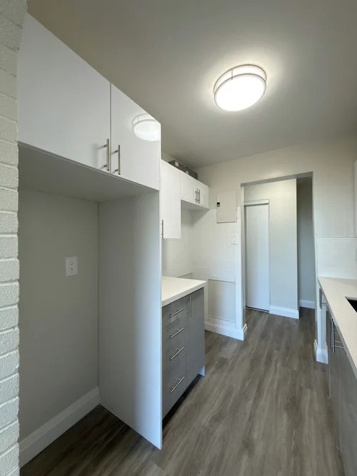 Finished kitchen with white wall cabinets and grey drawers on a new plank floor