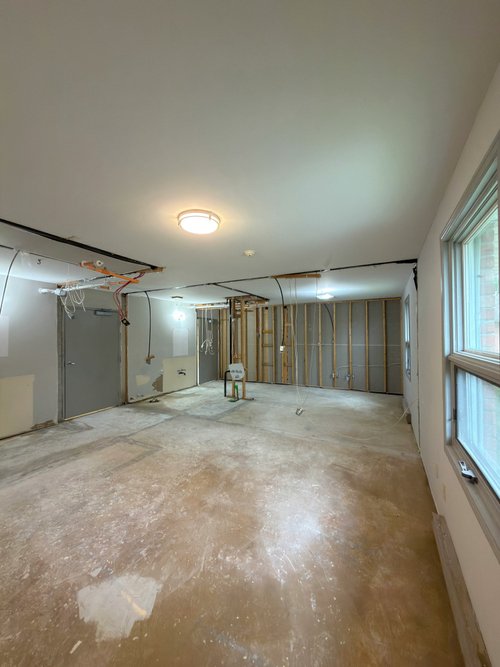 Gutted room with exposed wall studs, hanging wires and a bare floor