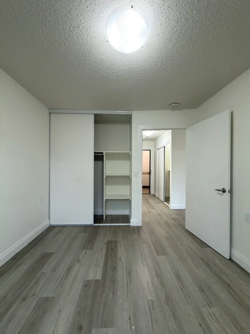 Finished bedroom with sliding closet doors and grey vinyl plank floor