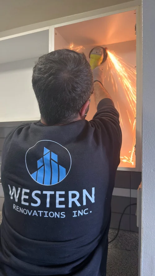 Crew member using an angle grinder with sparks flying inside an open cabinet
