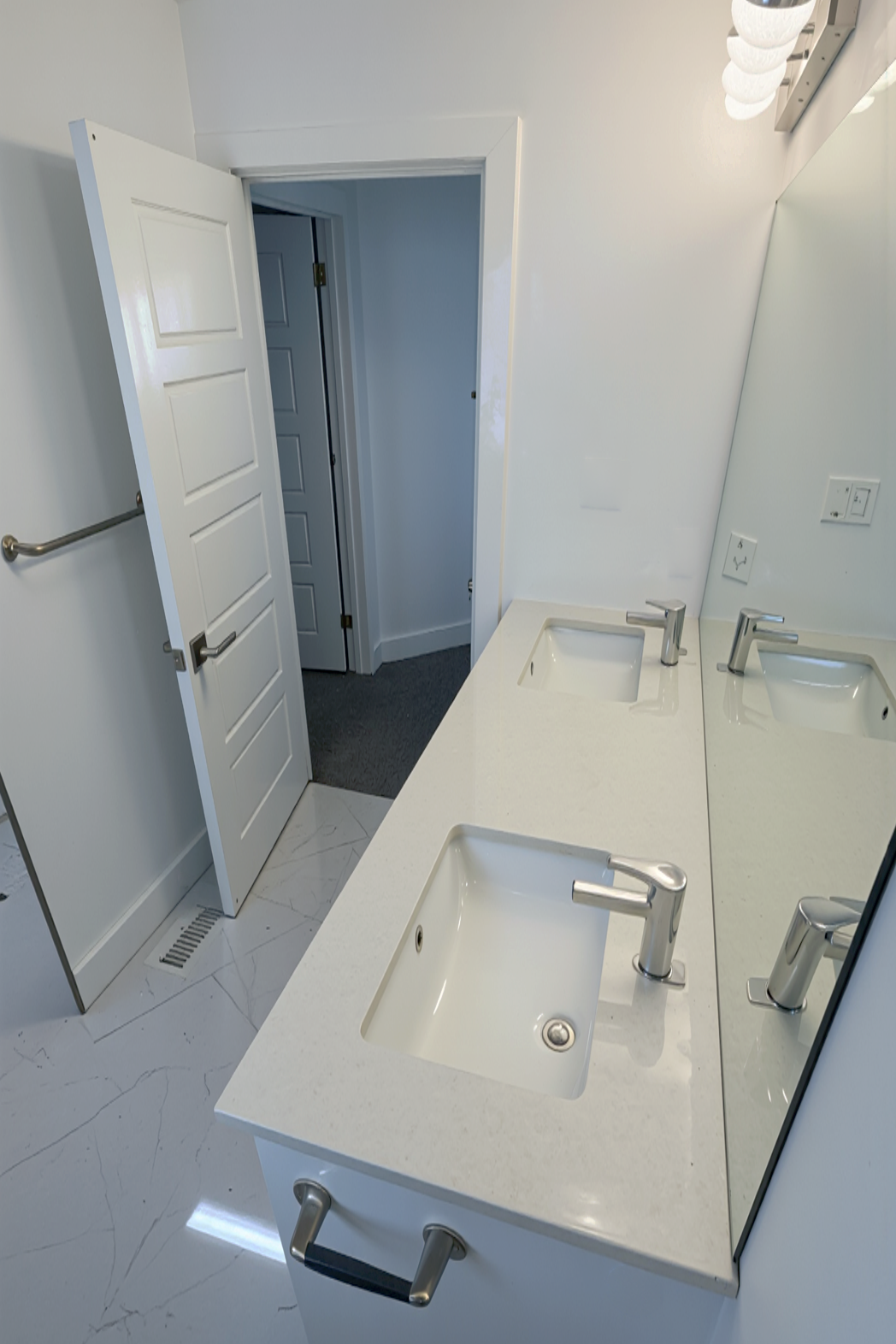 Contemporary bathroom renovation with double sinks and clean white finishes by Western Renovations Inc.