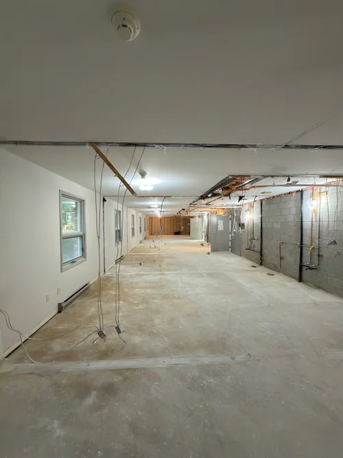 Gutted room with bare concrete floor and wiring hanging from ceiling