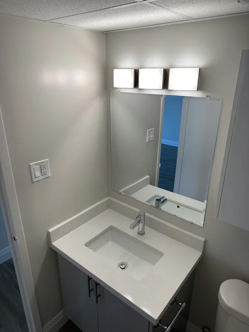 Finished bathroom vanity with three-light fixture above a light counter