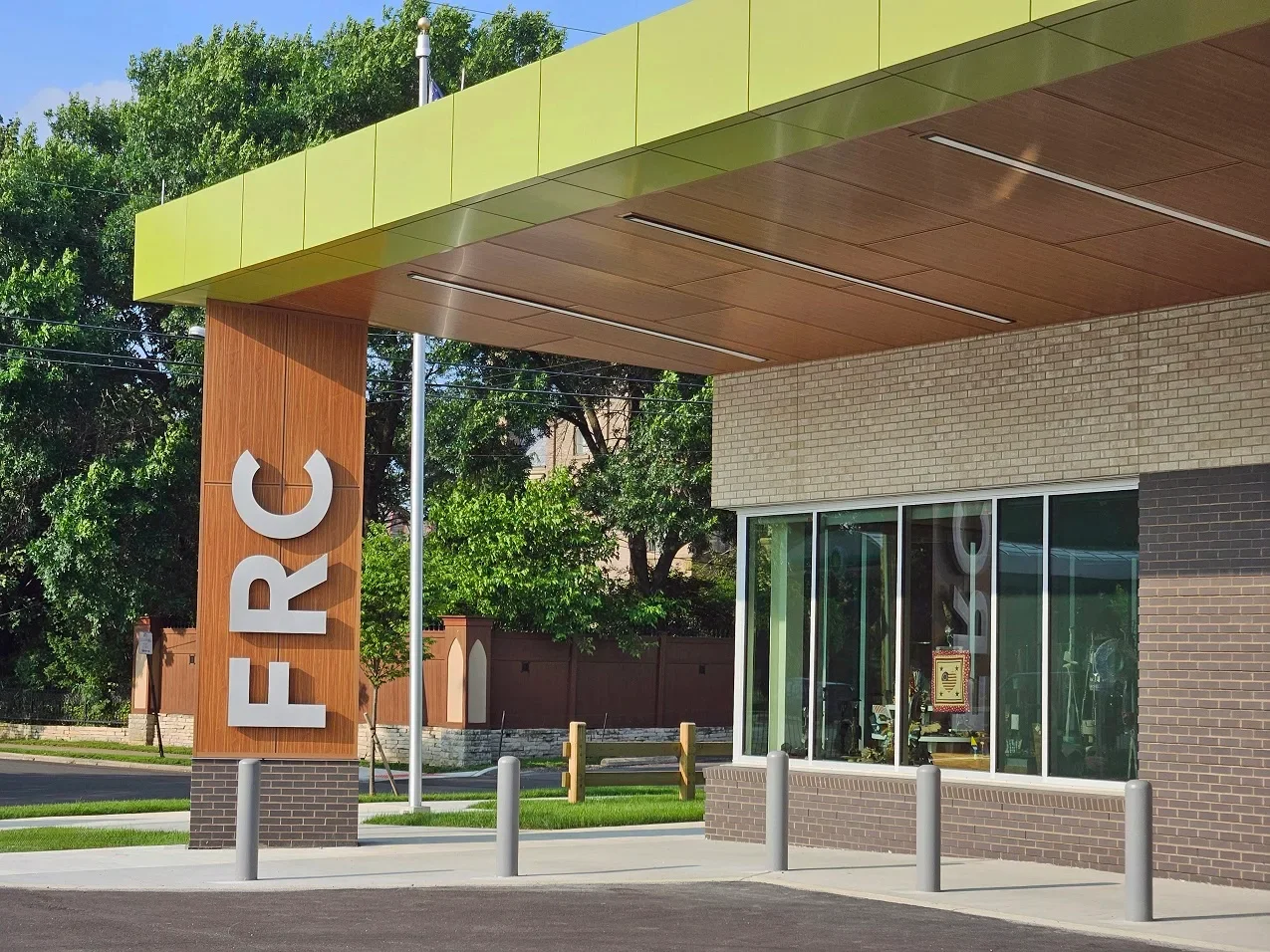 Fran Ryan Center with a large vertical sign and glass windows, surrounded by trees, bollards, and a sidewalk.