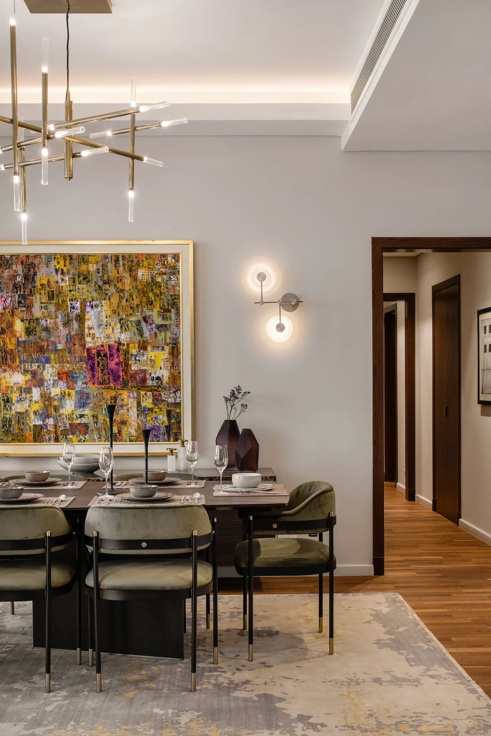 Modern dining room with a six-person table, velvet chairs, abstract artwork, decorative vases, and contemporary lighting fixtures.