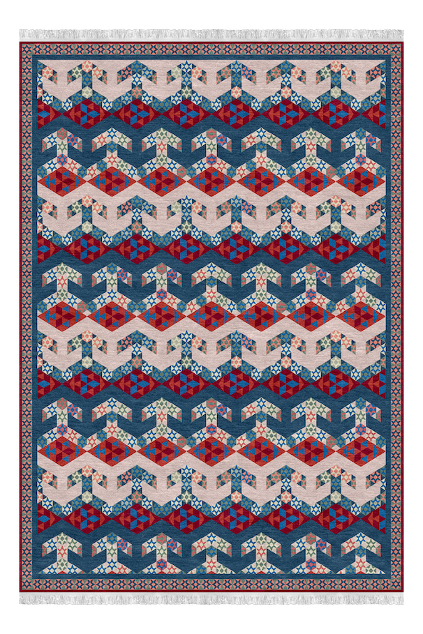 A colorful quilt with a repeating geometric pattern of interlocking shapes in shades of blue, red, beige, and pink, bordered by intricate geometric borders.
