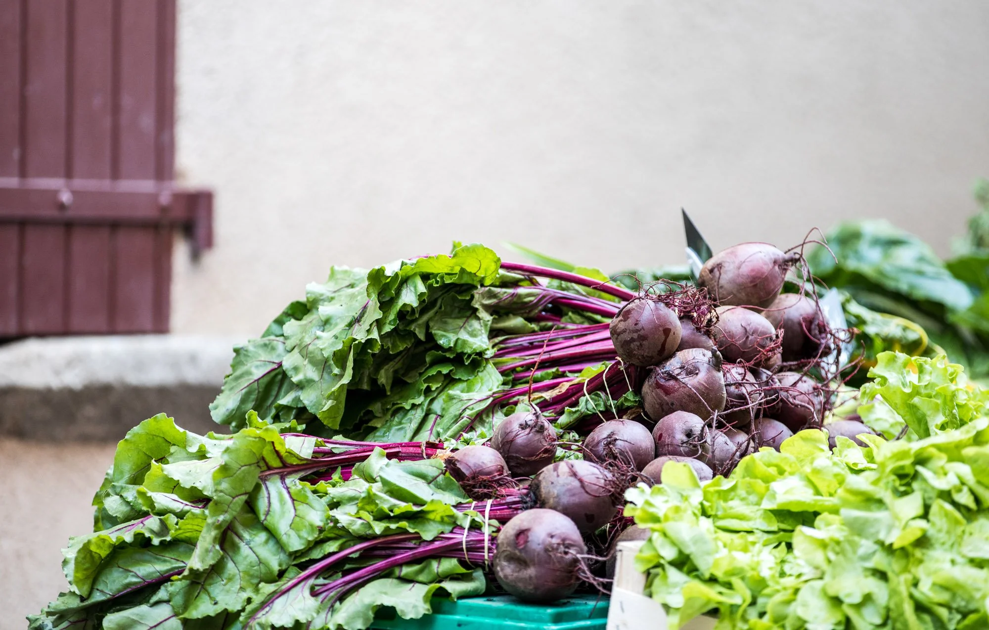 Fresh beetroots with green leaves on display at a farmers market.