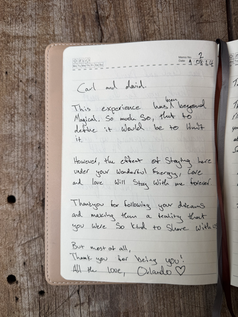 Open notebook on wooden surface, handwritten message from Orlando to Carl and David expressing gratitude and love.