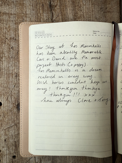 Open notebook on a wooden surface, with handwritten text about a memorable stay at the Mermonells and appreciation for Carl and David, signed by Clare and Tony.