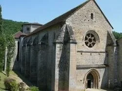 Stone church with arched windows and a circular window above the entrance in a rural setting.